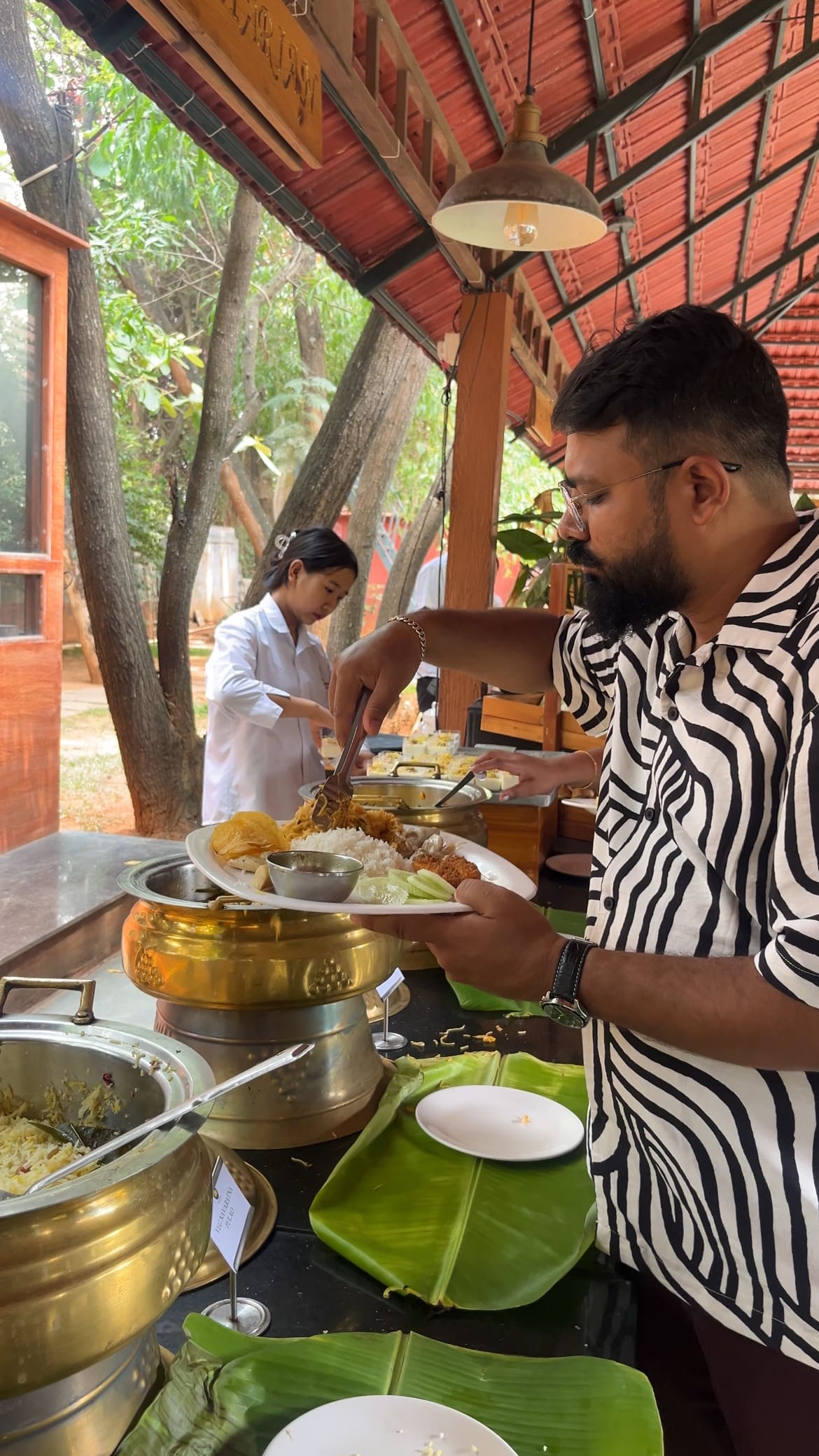 Buffet lunch counters laid out with vegetarian and non-vegetarian dishes and a server plating
