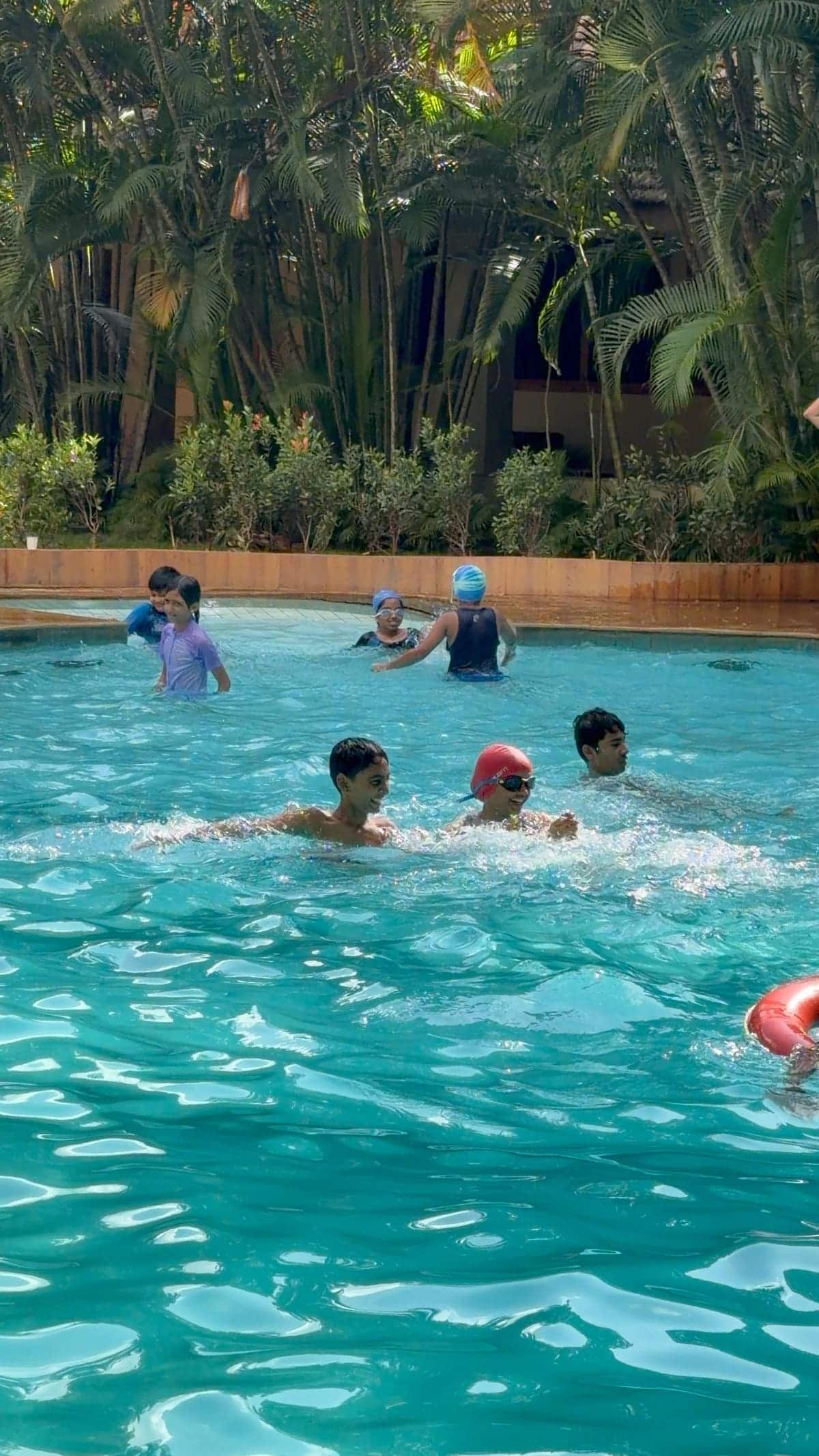 Guests swimming in the main pool on a busy Sunday, shot from the deck