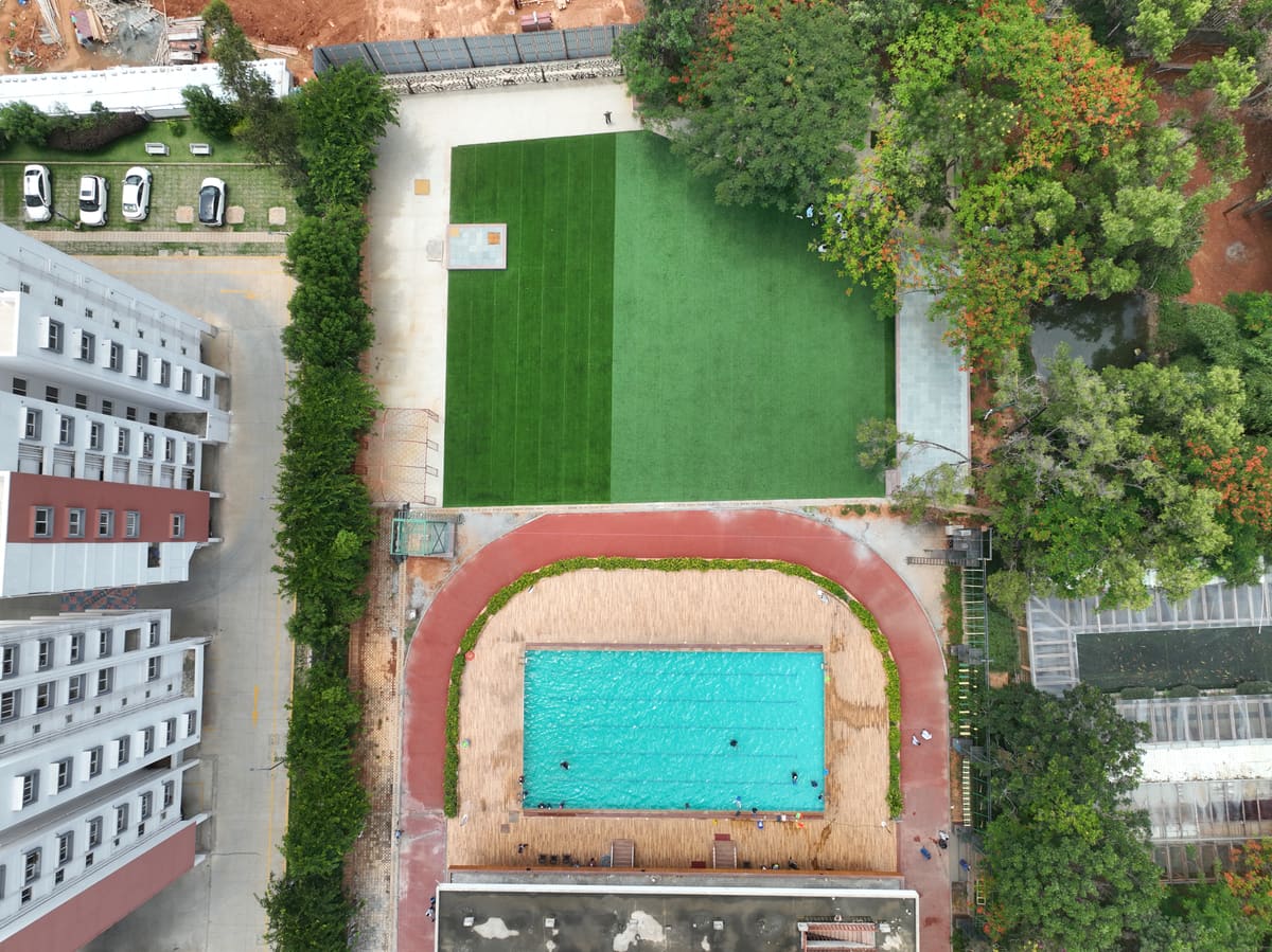 Drone shot directly overhead of the entire property showing the pool, both lawns, the banquet hall and the room blocks in one frame