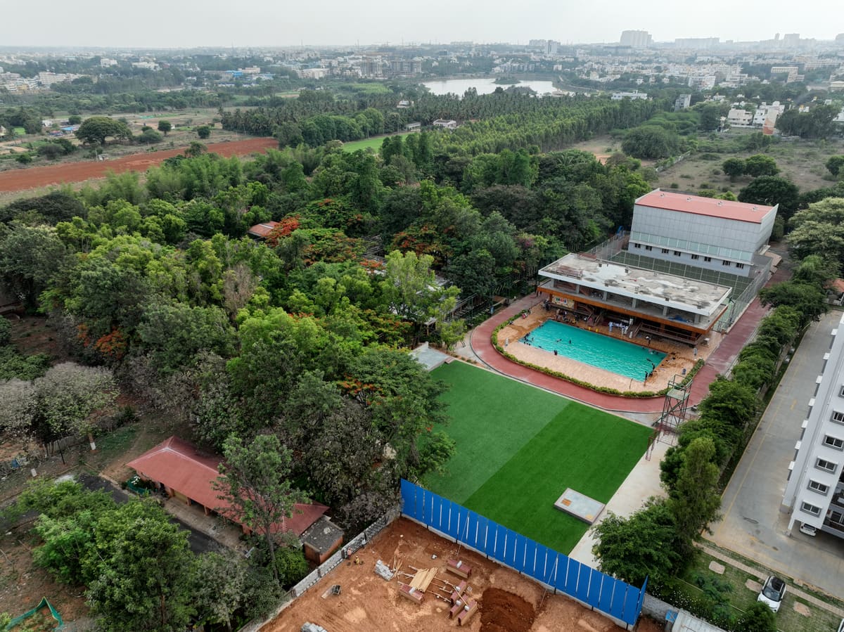 Drone shot from height showing the resort in relation to Huskur Road and the Electronic City skyline in the distance
