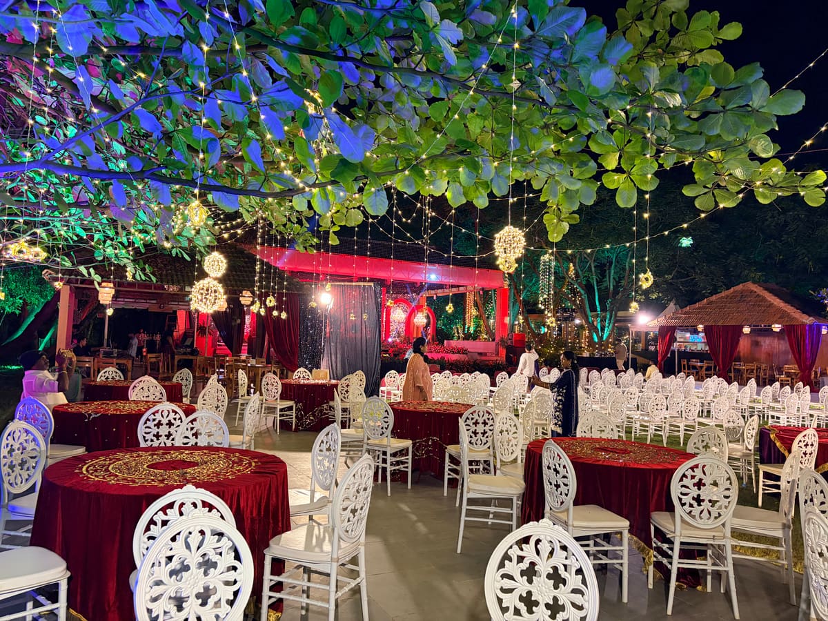 Main lawn set for an evening reception with round tables and decor lighting overhead