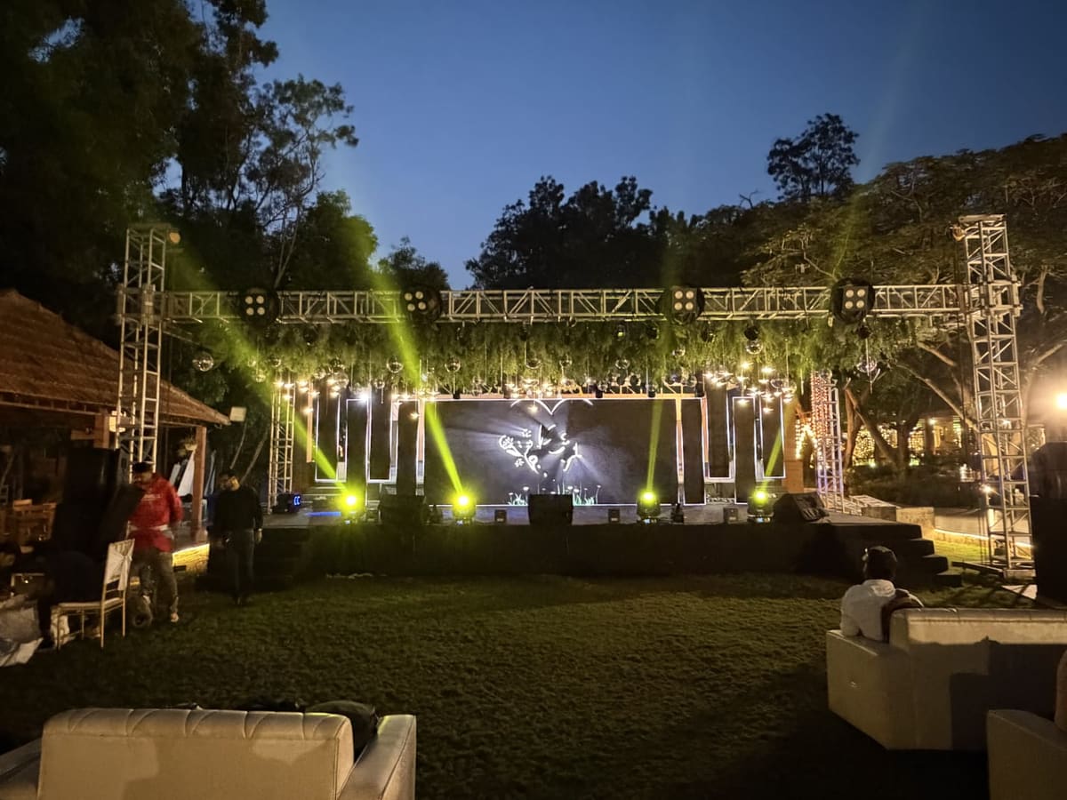 The stage and lighting rig lit for an evening event on the lawn