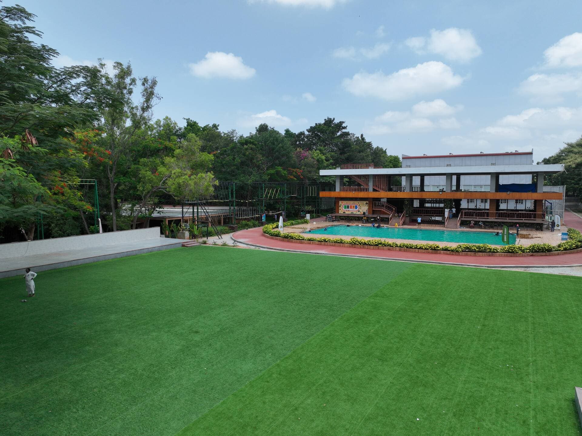 Wide golden-hour view across the pool towards the main lawn and banquet hall