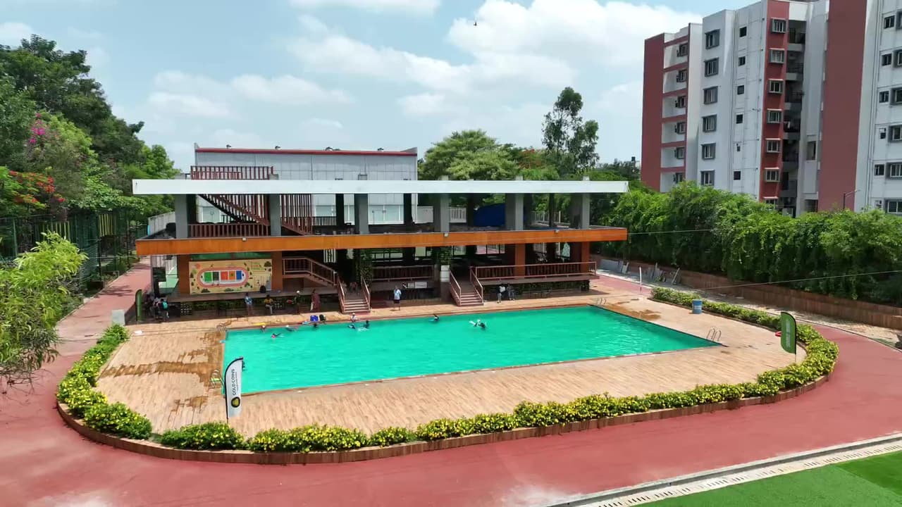 The swimming pool and clubhouse from the air with guests in the water on a day outing