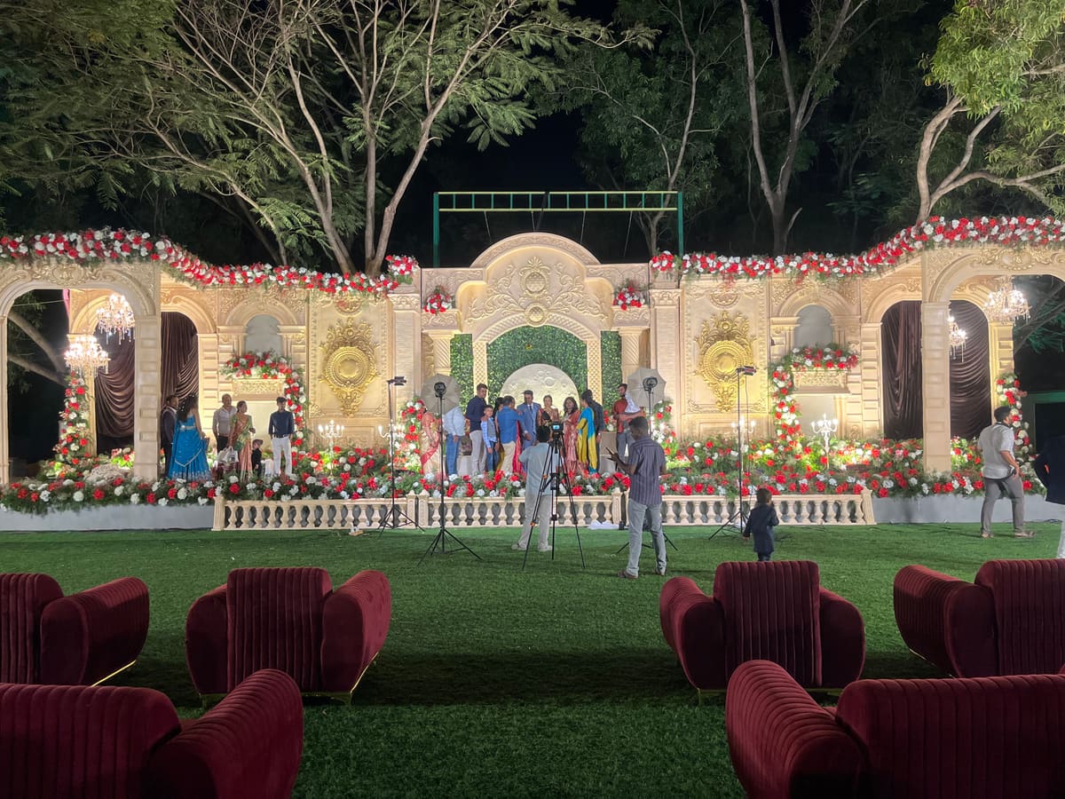 Main lawn set for an evening wedding reception, stage lit, round tables laid across the grass